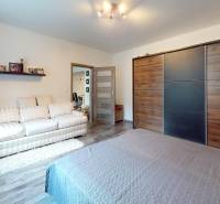 Bedroom in a family house with a sofa, wardrobe, and wooden decor flooring.