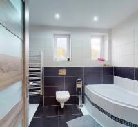 A bathroom in a family house with a bathtub, ladder radiator, and window.