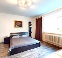 A bedroom in a family house with a bed, a wardrobe, and a floor with a wooden decor.