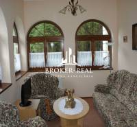 Living room with a floral sofa set, arched windows, and decorative paintings.