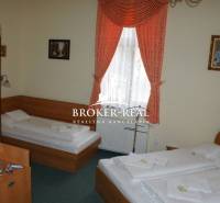 A hotel room with two beds, curtains, and paintings on the walls.