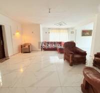 A spacious living room in a family house with comfortable leather furniture and fresh tiles.