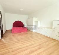 A room with a bed, white furniture, and a wooden decor floor in a family house.