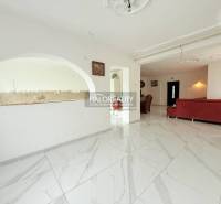 The interior of a family house with a white floor and a red sofa, open space, arched details.