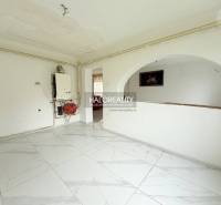 White room in a family house with tiles and an arched passage.