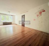 A spacious room with a wood-patterned floor and a large window in a family house.