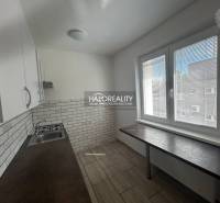 A kitchen in a 3-room apartment with white cabinets and textured tiles.