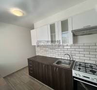 A kitchen in a 3-room apartment with white tiles and a wooden decor floor.