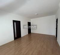 A room in a three-room apartment with a wooden decor floor and white walls.