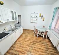 A kitchen in a family house with a wooden decor floor, a table, and white cabinets.