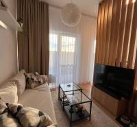 Living room with a comfortable sofa, glass table, and wooden-patterned floor.