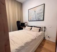A bedroom with a bed, a desk, and a wooden decor floor in a studio apartment.