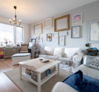 Living room with a comfortable sofa, wood-patterned flooring, and wall decorations.