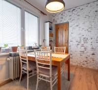 Dining area in a 3-room apartment with a brick wall and a wooden decor floor.