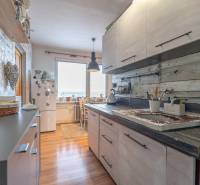 A kitchen in a 3-room apartment with a wooden decor floor and wall decorations.