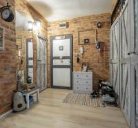 A hallway of a 3-room apartment interior with brick walls and a wooden decor floor.