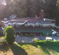 A cottage in Prašice surrounded by forests, with cars parked in front.