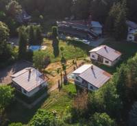 A cottage in Prašice with surrounding greenery and multiple buildings in a forest environment.