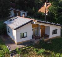 A cottage in Prašice surrounded by greenery, with a sloped roof and a veranda.