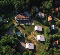 An aerial view of cottages in Prašice surrounded by dense forest and greenery.