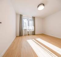 A room with a wooden floor decor, curtains, and a window in a 3-room apartment.