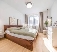 A bright bedroom with a comfortable bed, decorations, and a wooden-patterned floor in a 3-room apartment.