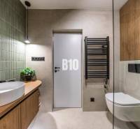 A bathroom in a 3-room apartment with wooden furniture, green tiles, and a wall-mounted drying rack.