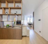 Interior of a 3-room apartment with an open living room, shelving wall, and flooring with a wooden decor.