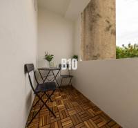 A balcony with two chairs and a table, flooring with a wooden decor in a three-room apartment.