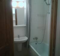 A bathroom with a bathtub and a sink in a studio apartment, reaching up to the ceiling.