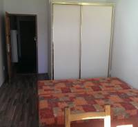 A room in a one-bedroom apartment with a bed, wardrobe, TV, and a floor with a wooden decor.