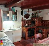 A kitchen with a tiled stove, a wooden-patterned floor, and a sink on a white counter.