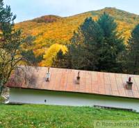 A cottage in Chocholná-Velčice surrounded by autumn forest and hills, a peaceful natural scenery.