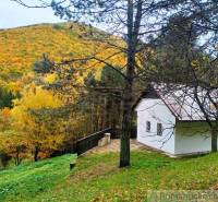 A cottage in Chocholná-Velčice near the forest with autumn colors on the hills.