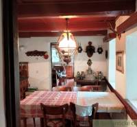 Dining room in a cottage with a wooden ceiling, decorations, and a set table.