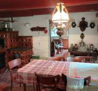 Rustic kitchen with a tiled stove and dining table in a cottage.