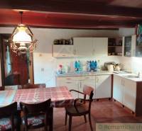 A kitchen in a cottage with a dining table, chairs, and rustic lighting.