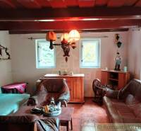 An old cottage with leather furniture, a wooden ceiling, and a tavern chandelier.