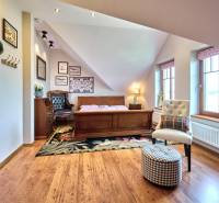 A room in a villa with a wooden-patterned floor, a cream chair, and wooden furniture.