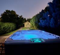 A nighttime hot tub in the yard of the Villa on Park Street in Hvezdoslavov, surrounded by trees.
