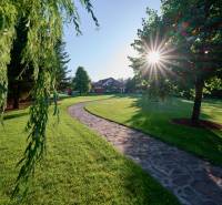 A stone pathway lined with trees in the garden of a villa on Parková Street in Hviezdoslavov.