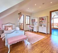 Children's room in a villa with white furniture, pink accessories, and a floor with a wooden decor.