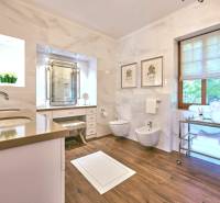 A bathroom in a villa with a wooden decor floor and marble walls.