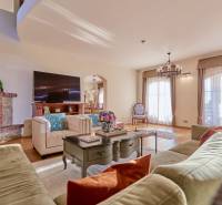A spacious living room in the villa with comfortable seating, a television, and a tiled stove.