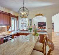 A kitchen in a villa with a marble island, decorative plates, and fruit.