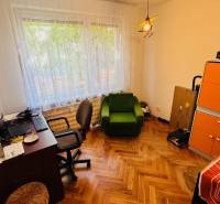 Office in a 3-room apartment with a wood-patterned floor, green chair, and cabinets.