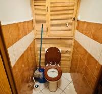 A toilet with ceramic tiles and a toilet brush in a 3-room apartment.
