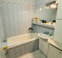 A bathroom with light tiles and a bathtub in a 3-room apartment.