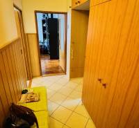 A hallway with tiles and wooden cabinets in a 3-room apartment.