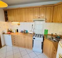 A kitchen with wooden decor, appliances, and a corner sink in a 3-room apartment.